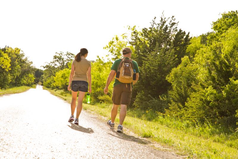 A man and woman hiking along a tree lined trail in Fredericksburg, TX