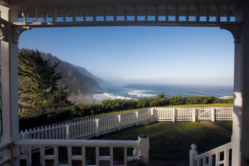 Heceta Head Lighthouse Bed & Breakfast by Heceta Head B&B Heceta Head Lighthouse Bed & Breakfast view shows a yard with white picket fence and coastal cliffs touching the Pacific