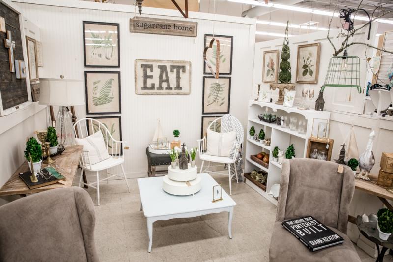 White-hued table and chairs with wall hangings in a display area of Redoux Market, Mandeville