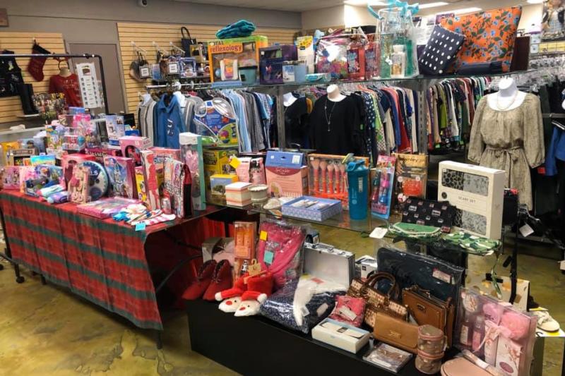 Tables of assorted toys and gifts sit in front of racks of women's clothes at Grans Attic, Mandeville