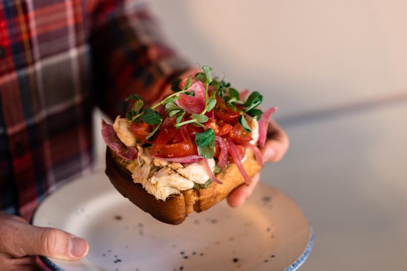 Men's hands holding Crab toast from The Atlantic on Pacific