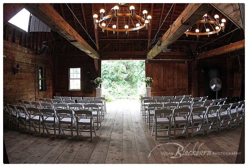 Barn set up for wedding with white chairs