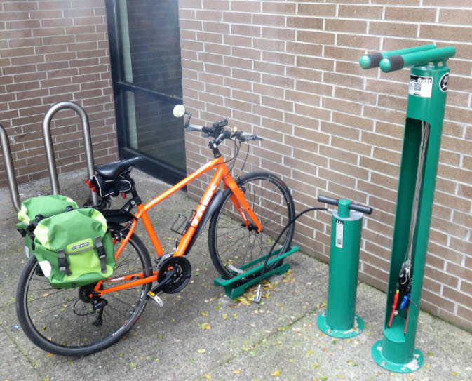 A bicycle at the bike repair station at the Sonoma Library, which has a green pump and a rack for working on your bike. There are bike tools hanging off of the rack.