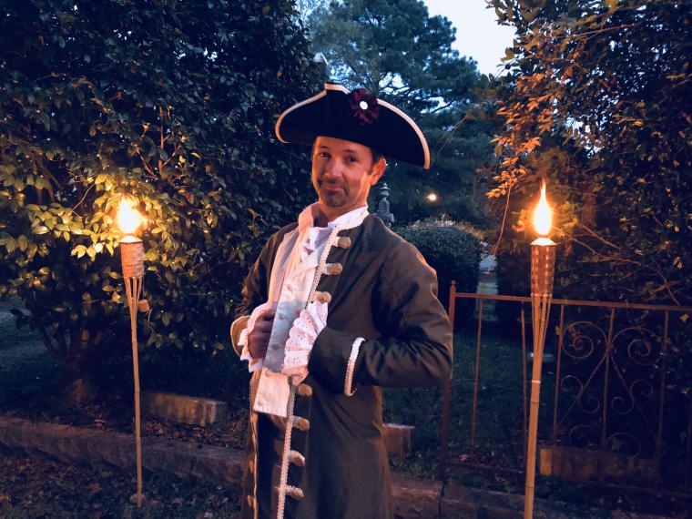 Man dressed in historical period clothes poses for the camera in a dimly lit cemetary for the Smithfield Ghost Walk