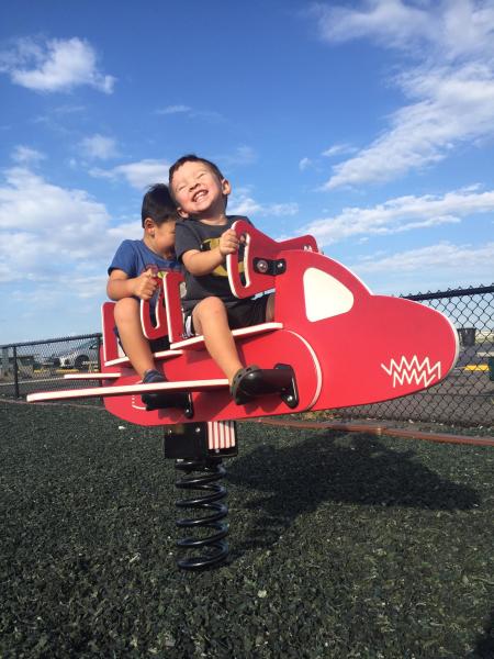 smiling boy on red airplane playground equipment at CVG airplane viewing area in hebron kentucky near cincinnati