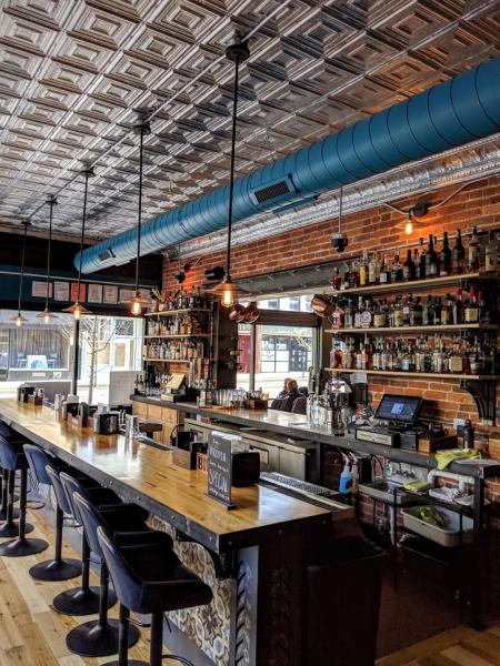 bar inside of Rich's Proper foods in covington ky with pendulum lights, blue hvac pipe, silver ceiling