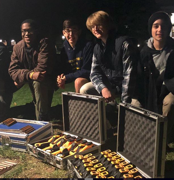 Four young men standing with ghost hunting equipment in suitcases