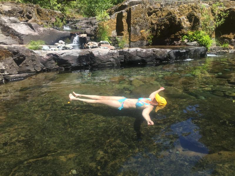 woman floats on her back in a clear natural pool at Brice Creek