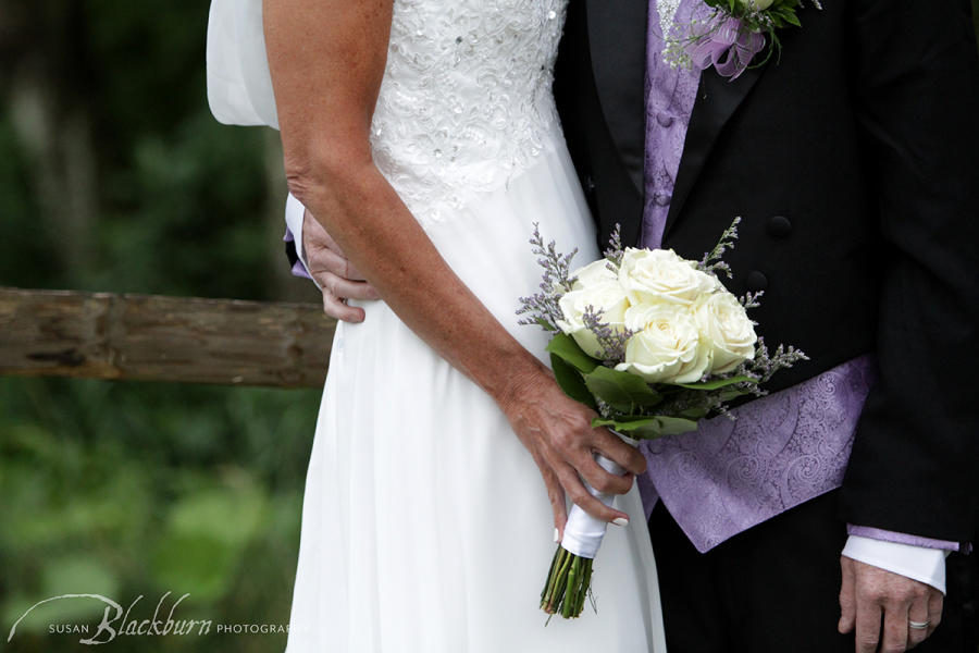 Couple holding white wedding bouquet with touch of purple