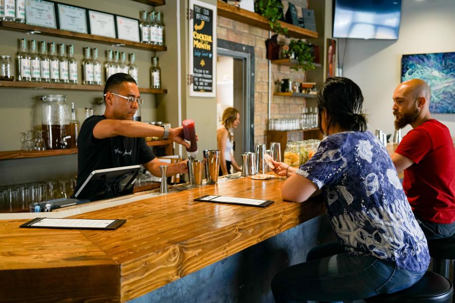 People at bar and bartender at SafeHouse Distillery, downtown Albuquerque