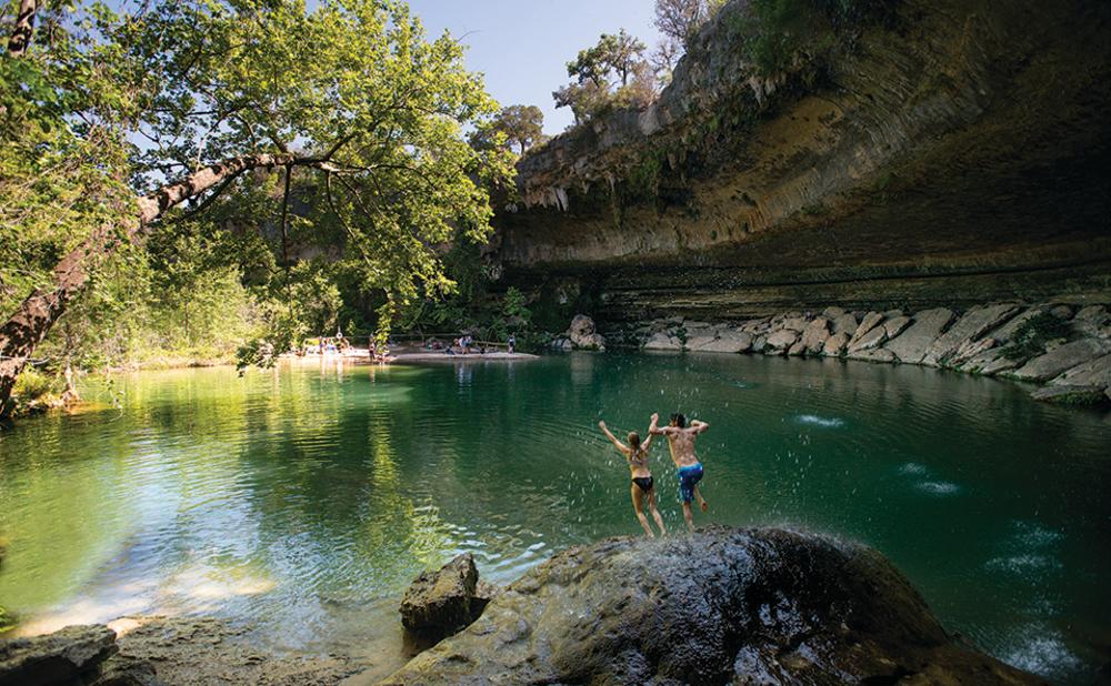 Couple jumping into Hamilton Pool