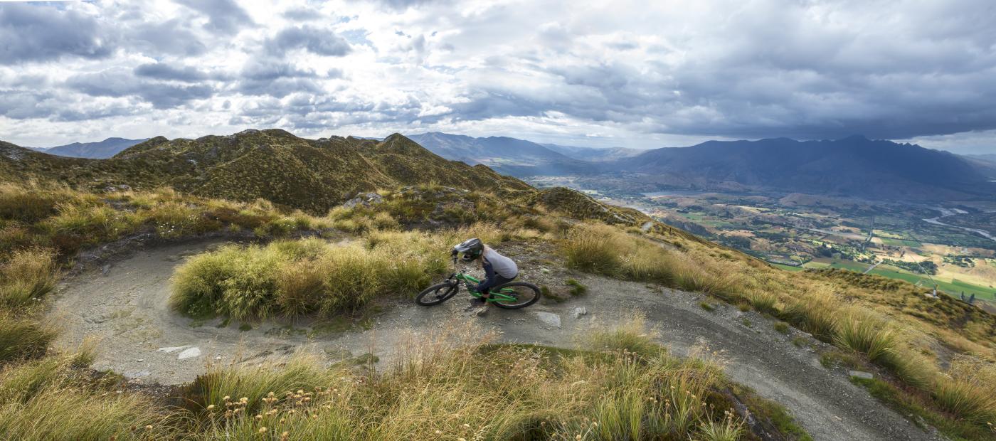 Female mountain biker riding Coronet Peak in summer