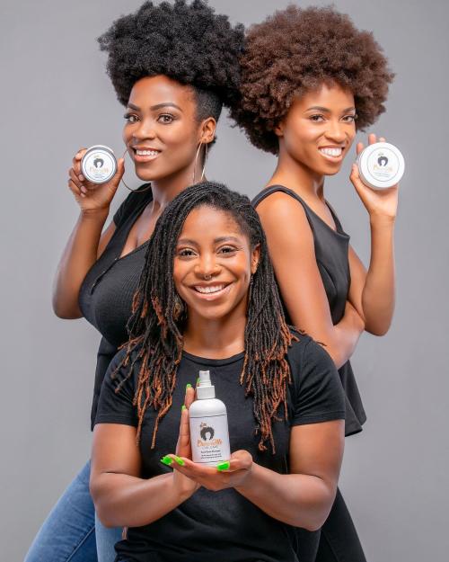 Three women pose with Arcani Coil Care hair product.