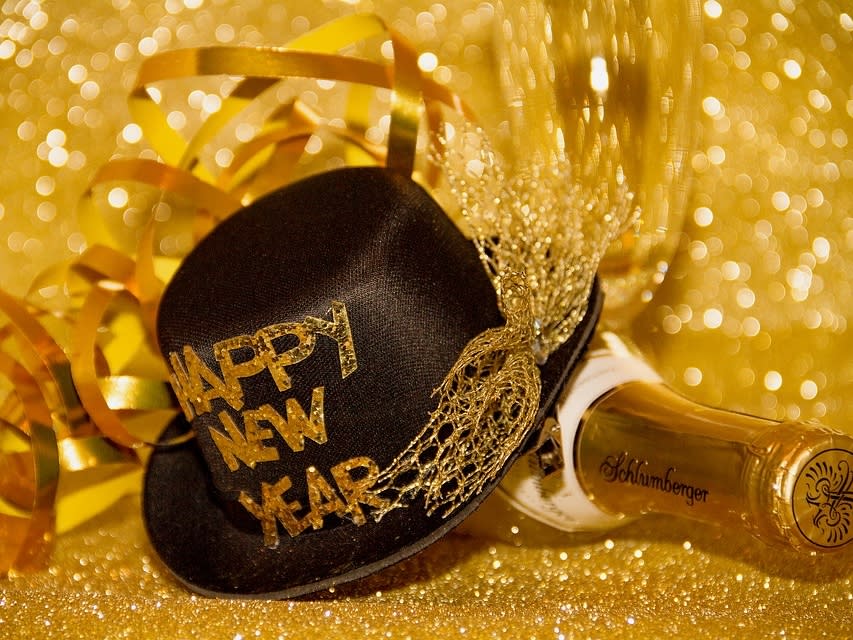Gold ribbons, a Happy New Year hat with gold letters, and a champagne bottle
