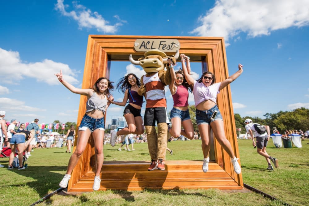 University of Texas Mascot Hook Em poses with women at the famed frame photo op at ACL Music Festival in Austin