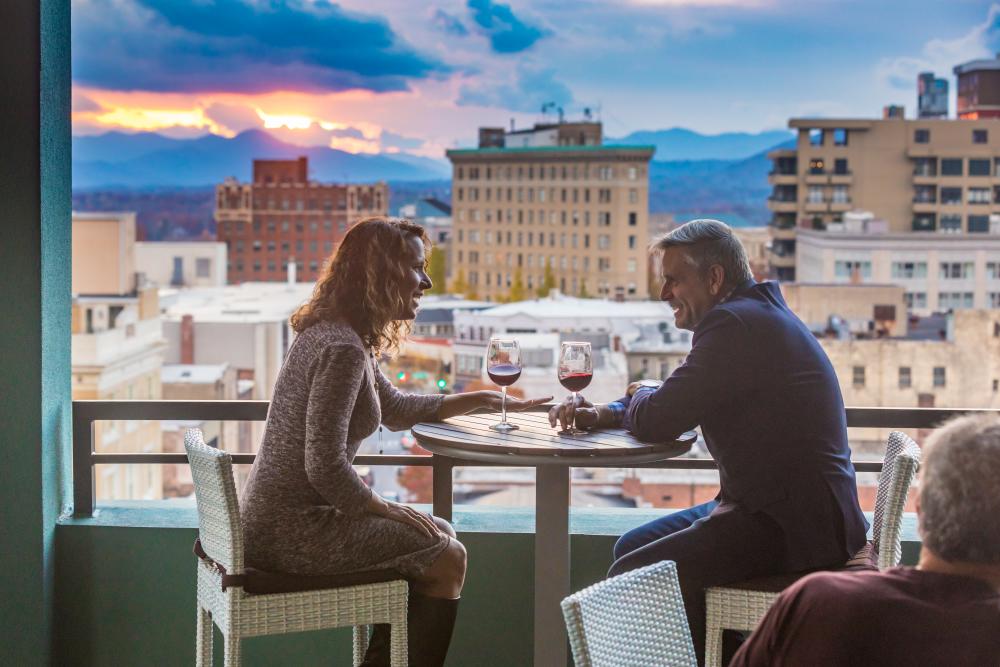 Couple enjoys glasses of wine atop the AC Hotel rooftop balcony.