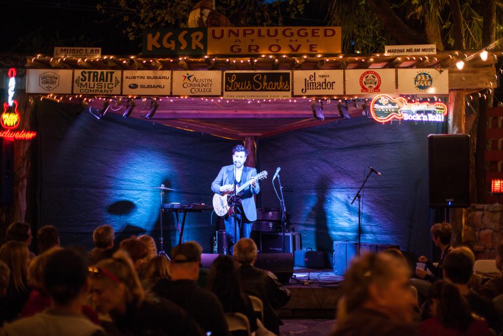 Bob Schneider plays guitar onstage at Unplugged at the Grove