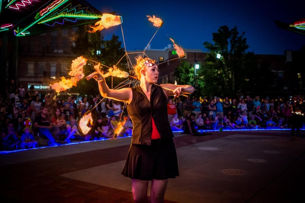 An artist performs her routine with fire in front of a large audience for First Friday in Wichita