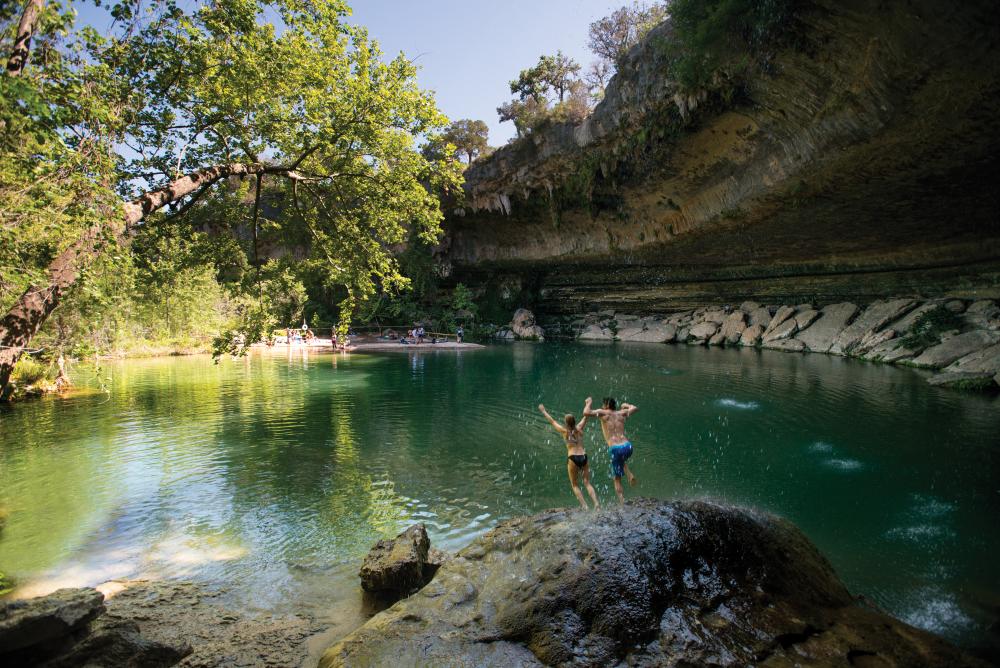 Couple jumping into hamilton pool in dripping springs near austin texas