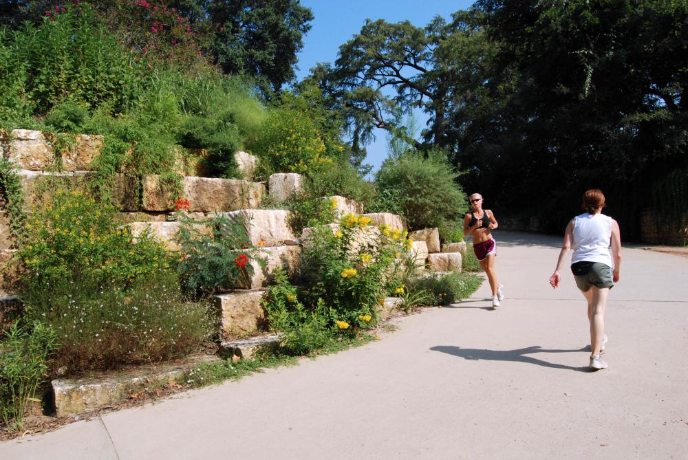 A runner passes a woman walking at Lou Neff Point at the Hike and Bike Trail