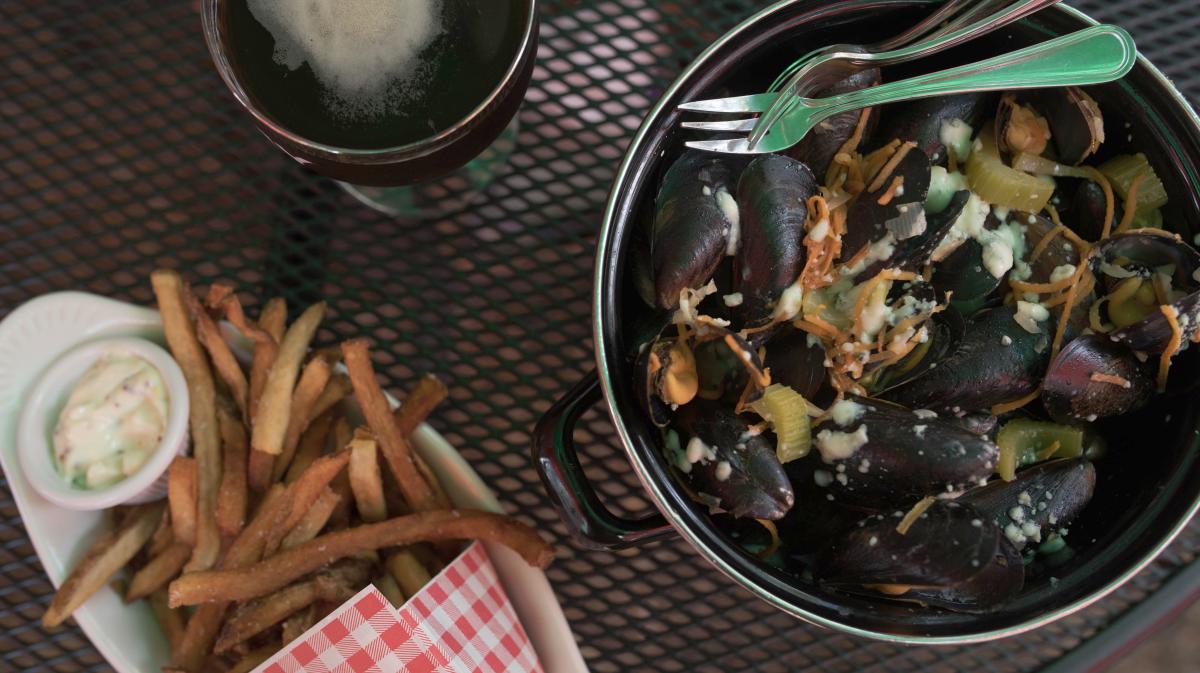 A pot of food with a plate of french fries next to it.