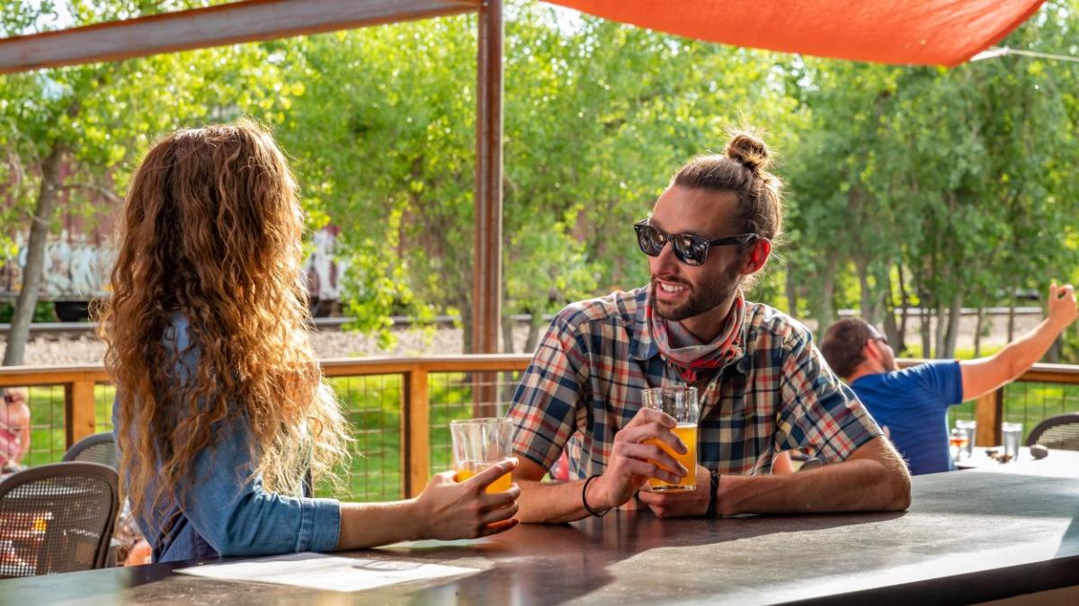 Man and woman drinking beer outside at Sanitas Brewing