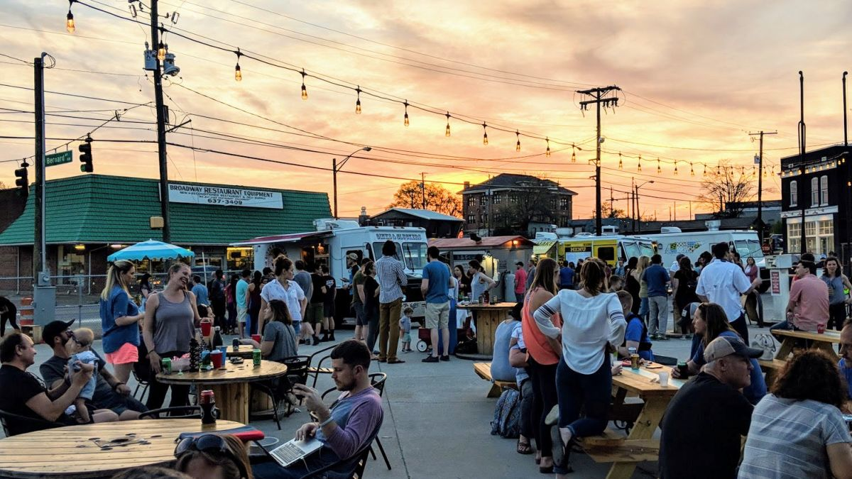 People standing and sitting at tables at a Food Truck Park