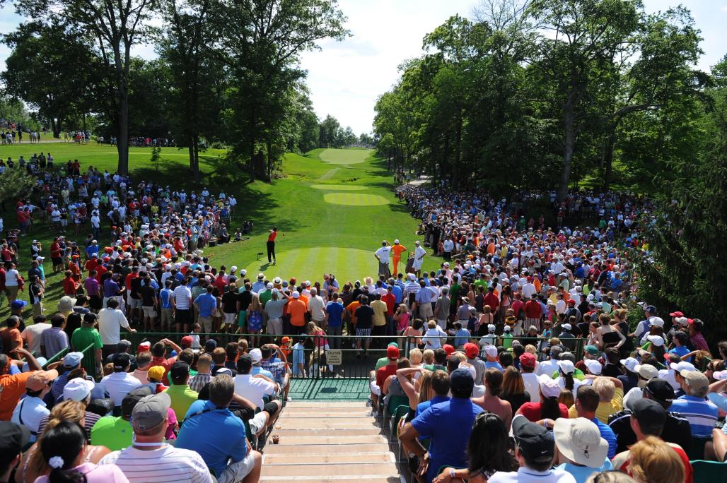 Golfer teeing off from the 15th tee at the Memorial Touranment while fans surround the tee box.