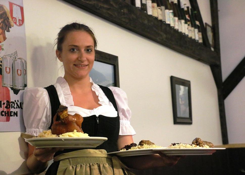 A server poses with two plates in hand at Rheinblick German Restaurant
