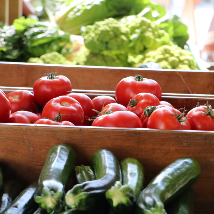 Zuchinni, tomato, and lettuce in boxes at a Farmers Market