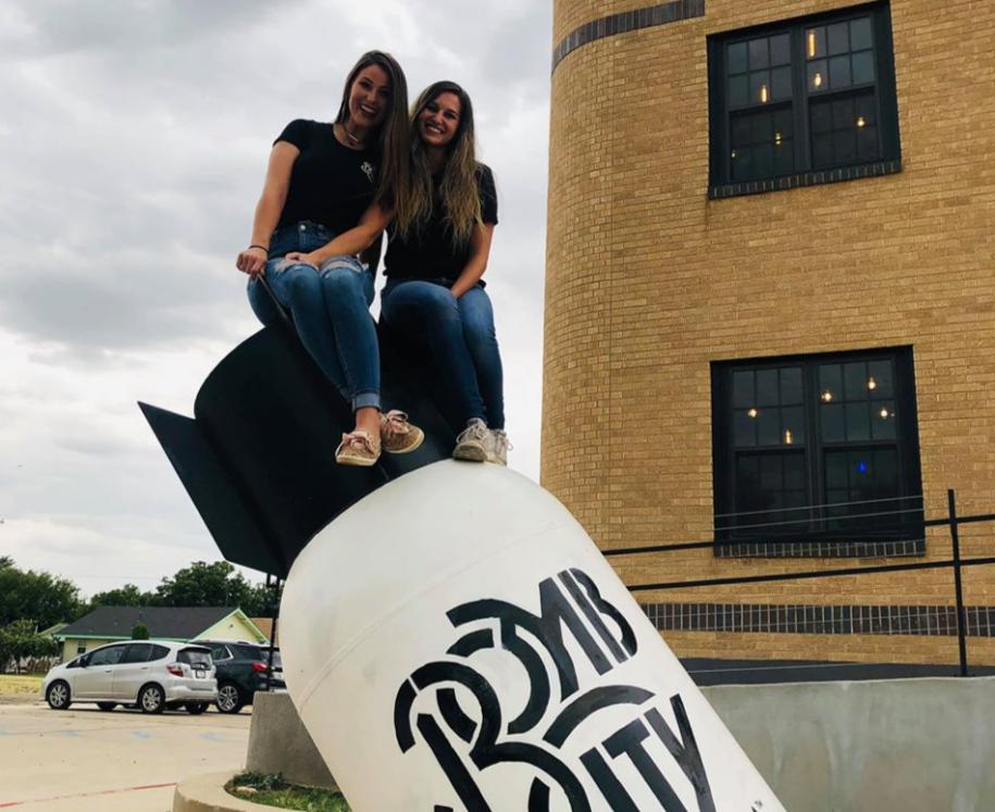 two girl sitting on statue at bomb city distillery in amarillo