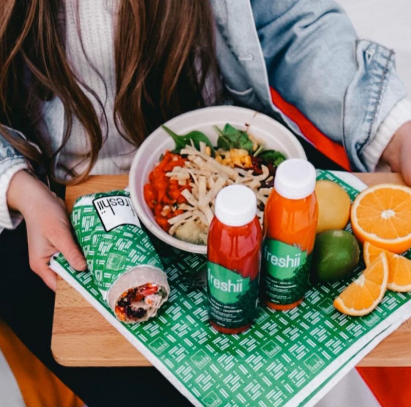 Woman Holding A Tray Of Food From Freshii In Irving, TX