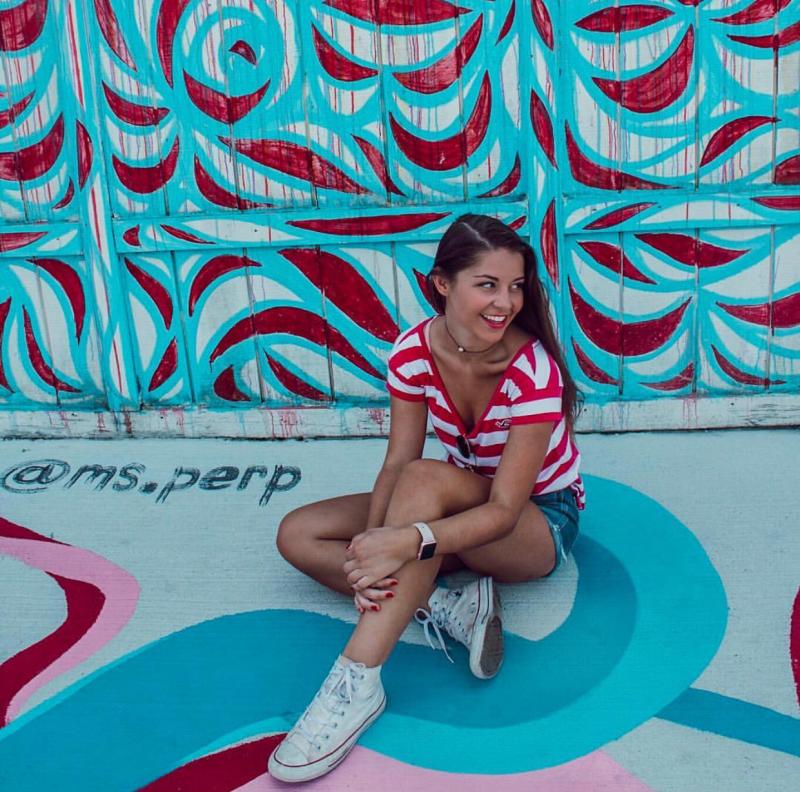 Woman Sitting In Front Of Vibe Creative District Mural In Virginia Beach