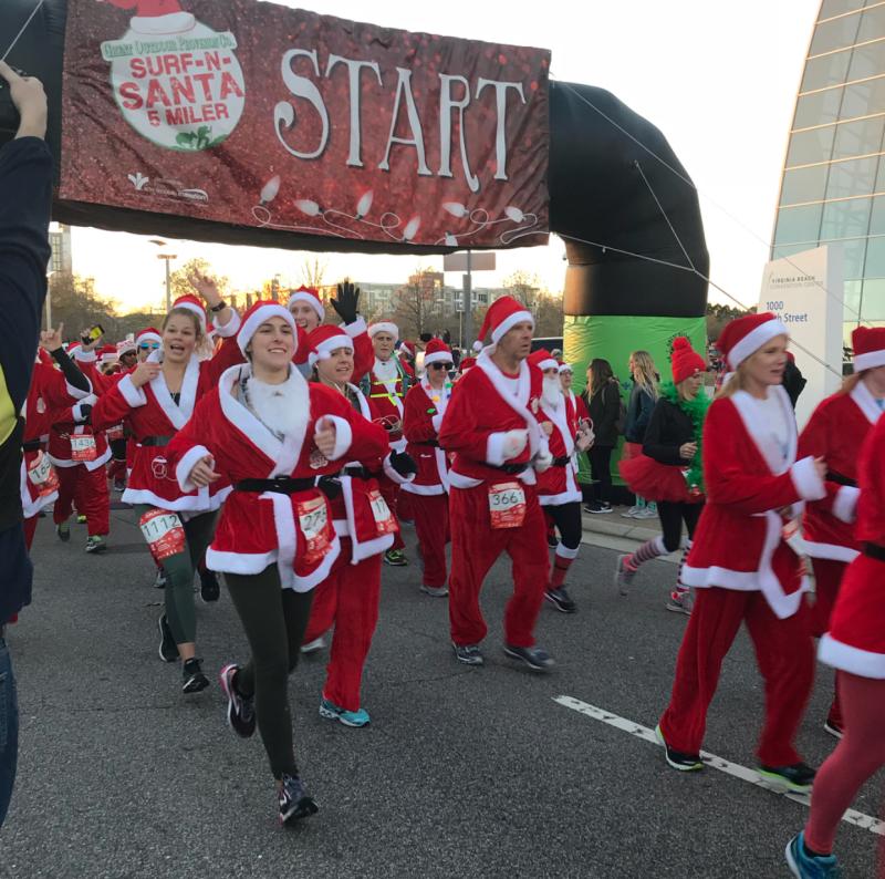 Mensen in kerstmannenpak lopen de Surf And Santa 5 Miler in Virginia Beach