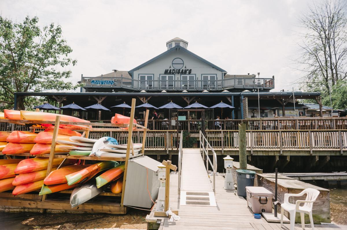 restaurant on the water with kayaks on the pier in front of the building