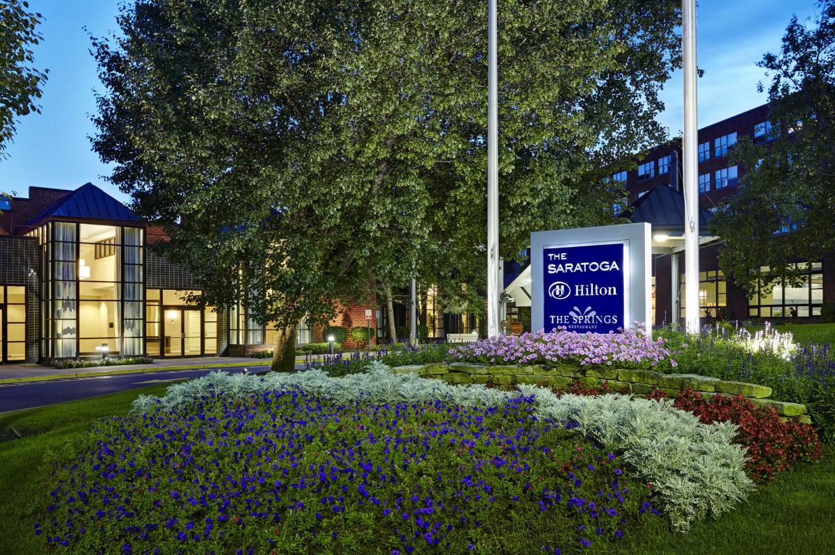 Outdoor hotel sign at night with flowers