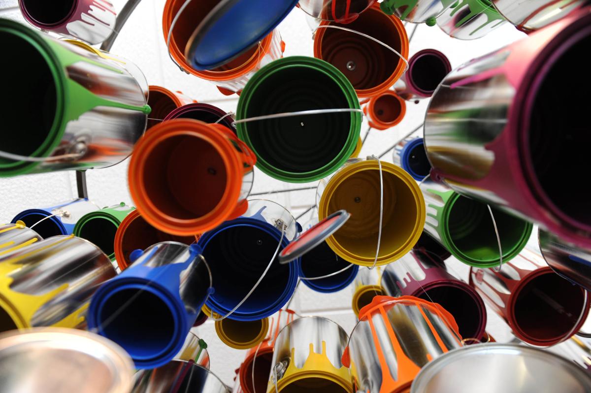 Art installation of multi-colored paint cans hanging from ceiling, photographed from below