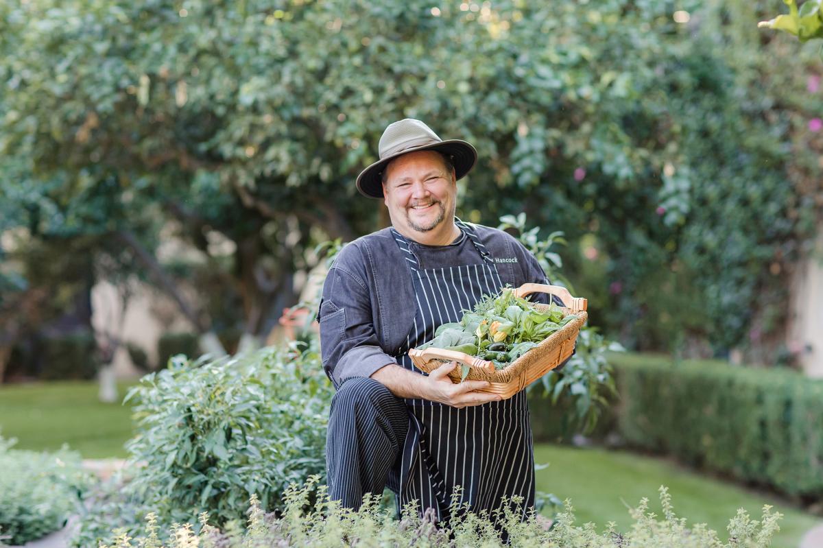 Smiling chef in garden holding a basket