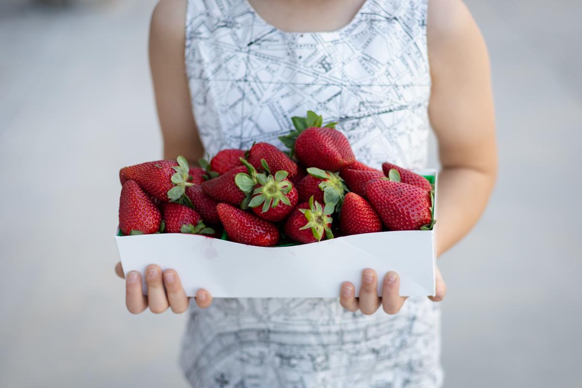 A child holds a flat of fresh, ripe strawberries found at an Irvine-area Farmer's Market.