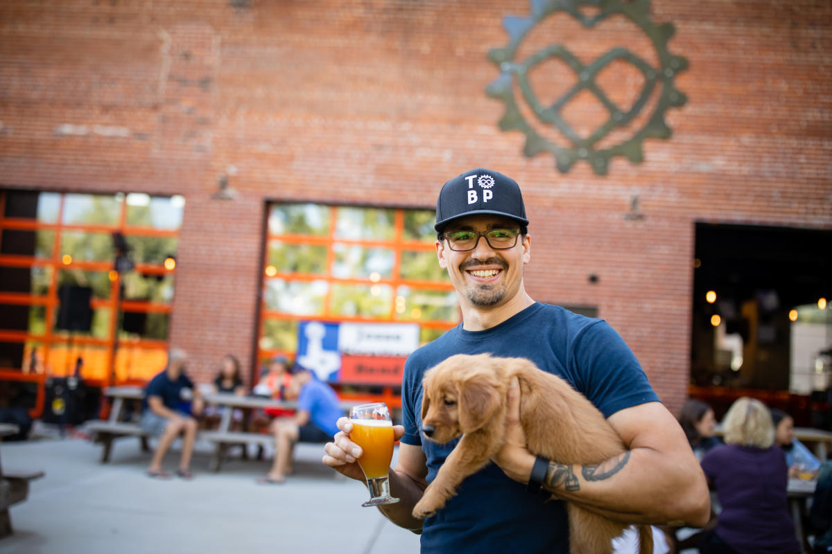 Man holding his puppy and a beer outside at the Brewing Projekt