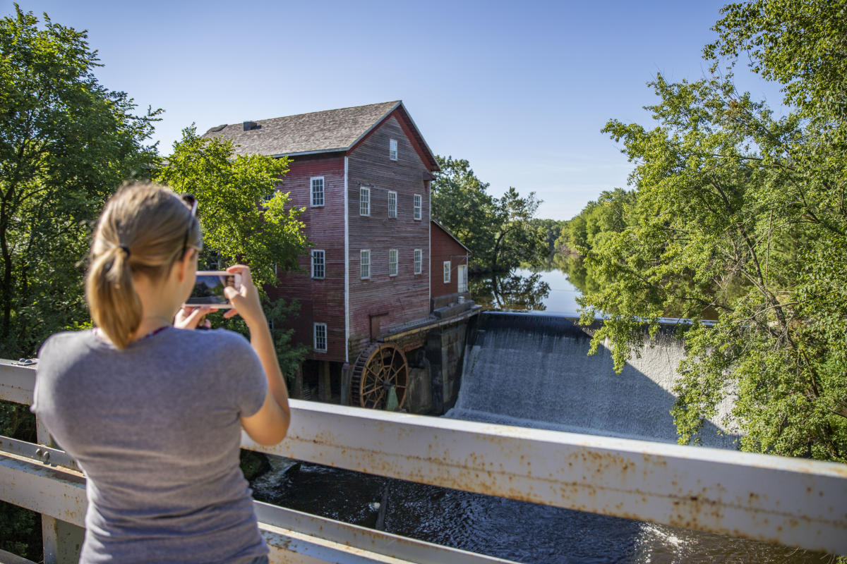 Woman Taking a picture of the Dells Mill Museum in the summer