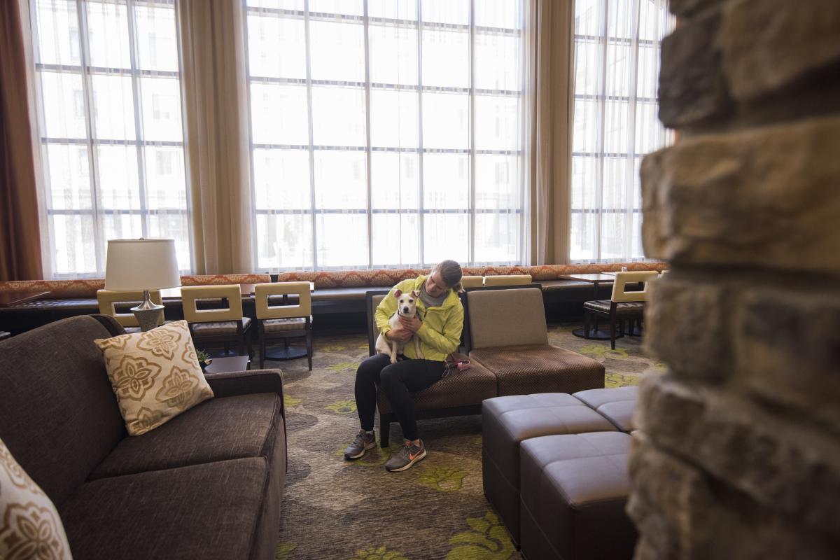 Woman holding a Jack Russell dog in a sitting area at the Staybridge Suites in Altoona, Wisconsin