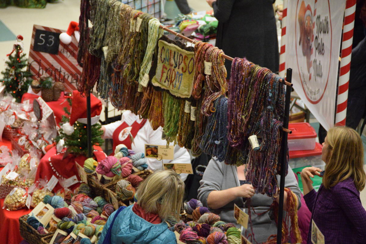 person standing in front of a booth with yarn skeins