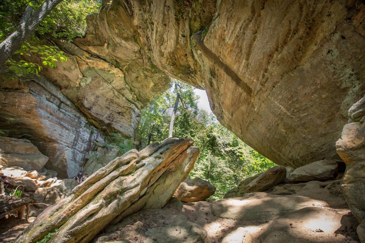 A large, natural stone arch with a forest visible through the arch.