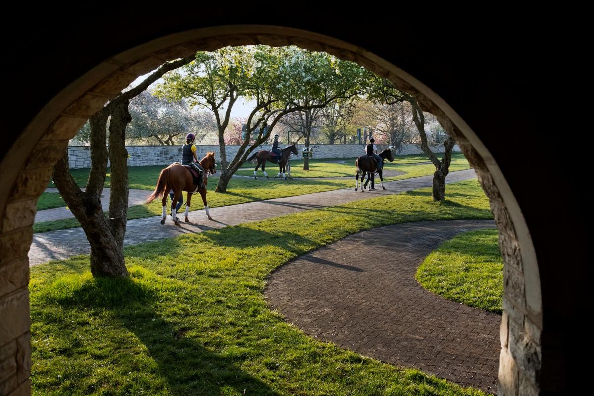 Jockeys ride their horses through curving brick pathways at Keeneland.