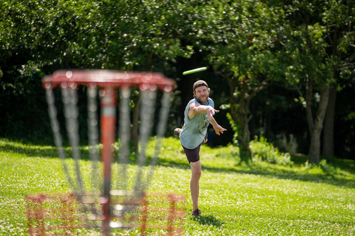 A man takes aim at a disc golf basket at Elver Park