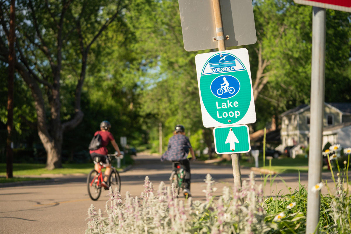 Bicyclists ride past a Lake Monona loop sign