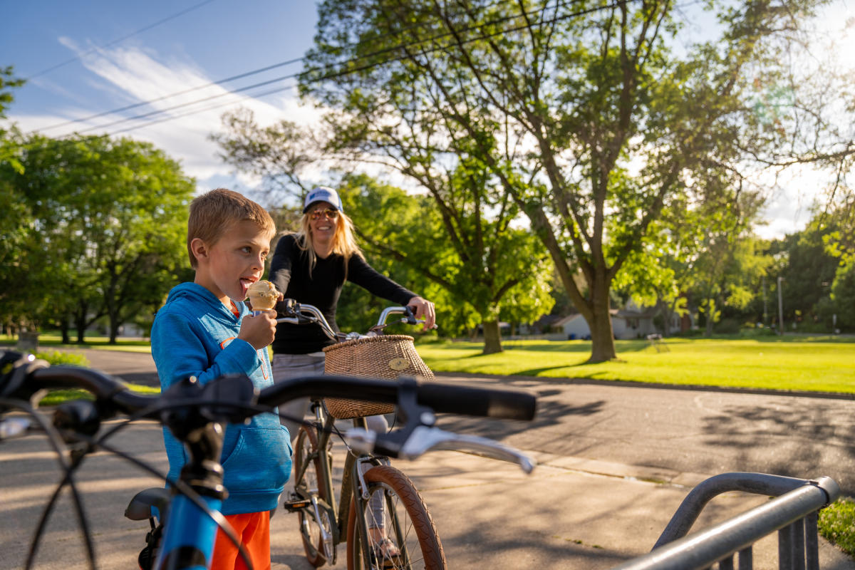 A boy takes a break from biking to enjoy an ice cream cone