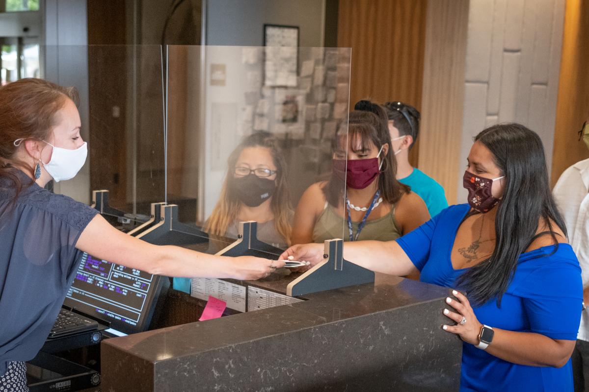 Guests wearing masks check in at a hotel