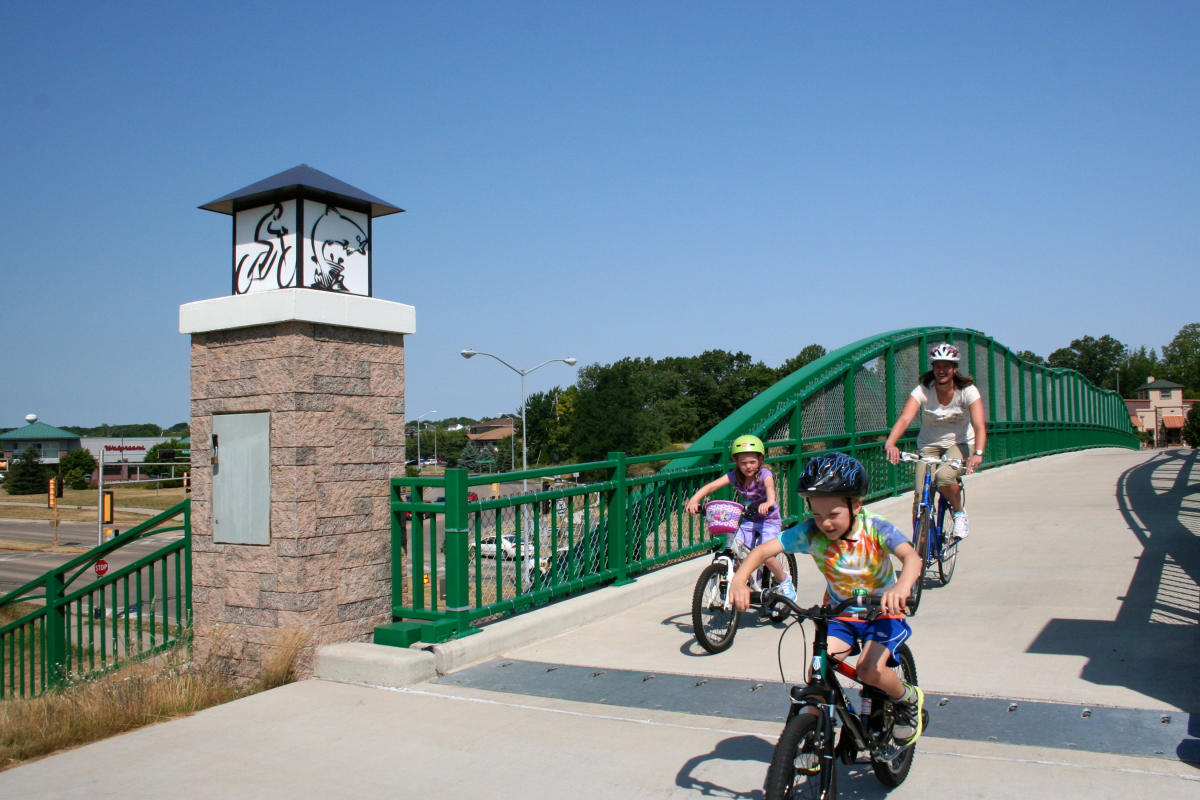 A woman and a little boy and girl bike over a bridge in Fitchburg